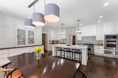 a kitchen with stainless steel appliances granite countertop a stove top oven a sink a dining table and chairs with wooden floor