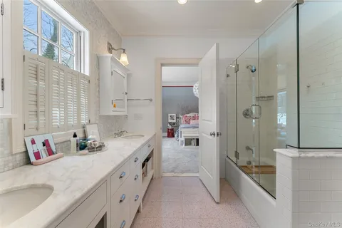 a bathroom with a granite countertop double vanity sink a shower and a mirror