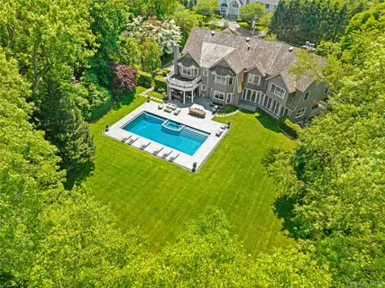 an aerial view of residential house with outdoor space and trees all around
