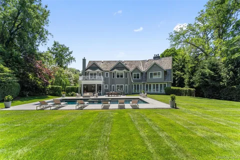 a view of pool with lawn chairs and large trees