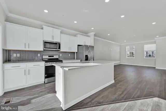 a kitchen with stainless steel appliances a sink a stove a microwave a center island and cabinets