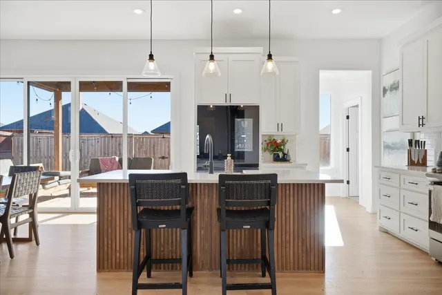 a kitchen with stainless steel appliances kitchen island granite countertop a table chairs sink and cabinets