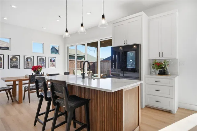 a dining hall with stainless steel appliances kitchen island granite countertop a table chairs and a refrigerator