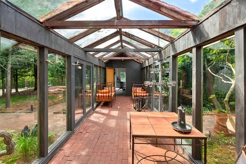 a view of a patio with table and chairs potted plants with wooden floor and floor to ceiling window