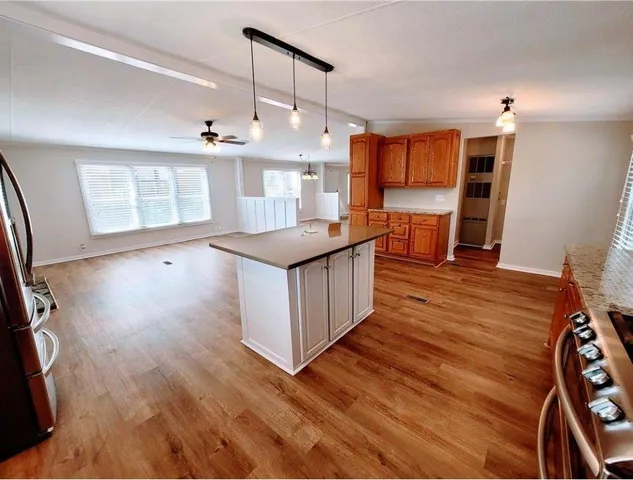 a kitchen with stainless steel appliances kitchen island wooden floors granite counter tops and a window