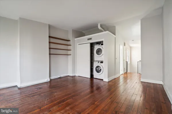 a view of a hallway with wooden floor and a refrigerator