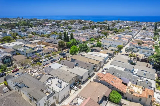 an aerial view of a city with lots of residential buildings and ocean view in back