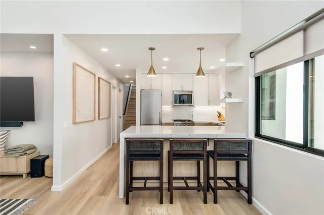 a kitchen with kitchen island a dining table chairs stainless steel appliances and cabinets