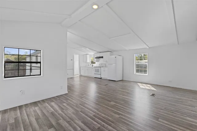 a view of empty room with wooden floor and window