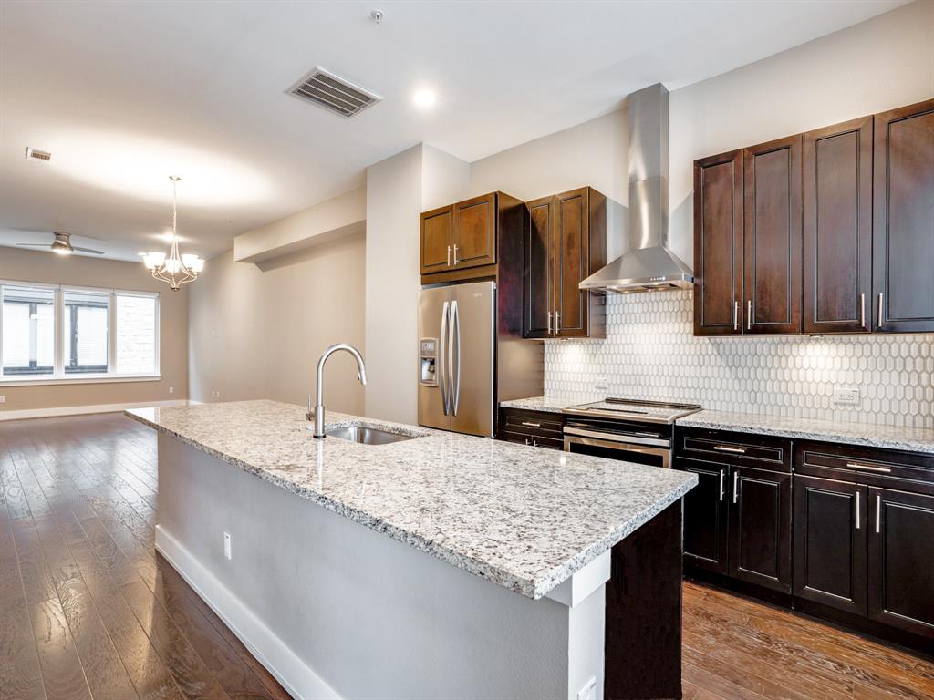 a kitchen with granite countertop kitchen island stainless steel appliances a sink stove and cabinets