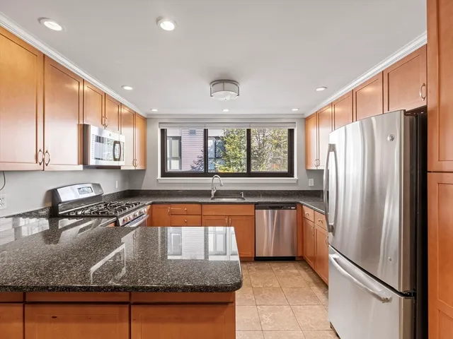a kitchen with stainless steel appliances granite countertop a refrigerator a sink and a stove