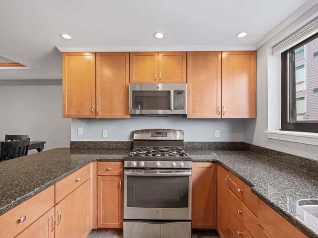 a kitchen with stainless steel appliances granite countertop a stove a sink and a microwave