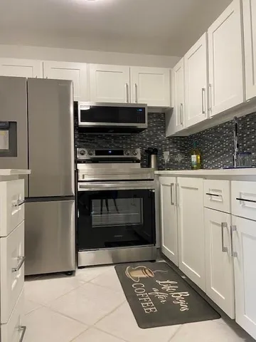 a kitchen with granite countertop a stove a refrigerator and a stove top oven