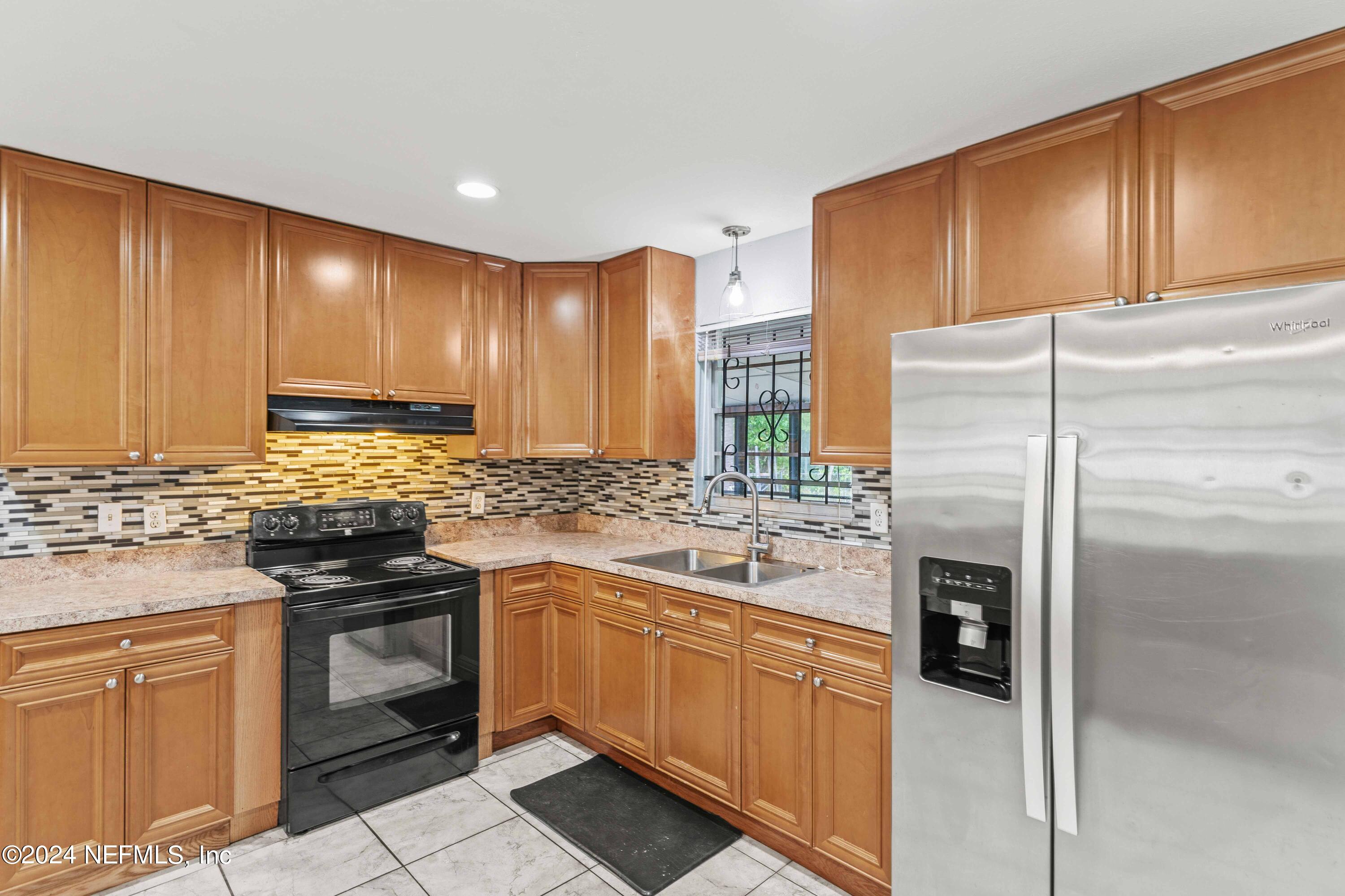 8545 Addison Road Jacksonville, FL 32208 - Photo 4 of 26 a kitchen with stainless steel appliances granite countertop a stove a sink dishwasher and a refrigerator with wooden cabinets