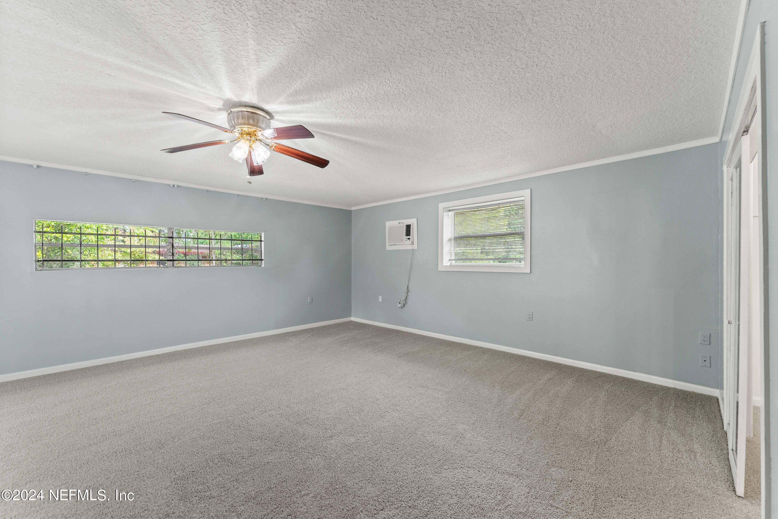 8545 Addison Road Jacksonville, FL 32208 - Photo 10 of 26 an empty room with windows and chandelier fan