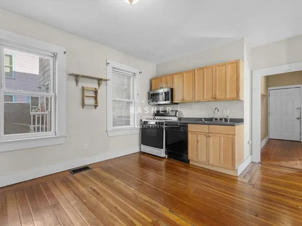 a kitchen with stainless steel appliances a stove a sink a microwave and wooden floors