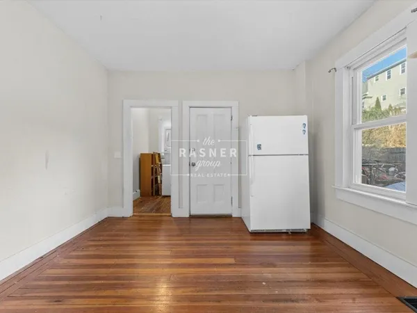 a view of a livingroom with wooden floor and a refrigerator