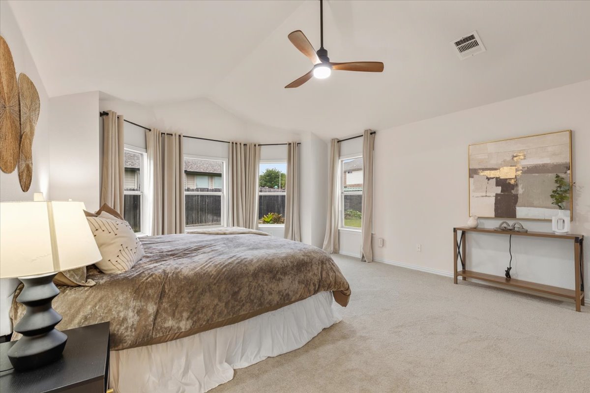2501 Aspen Meadow Road Leander, TX 78641 - Photo 11 of 30 Spacious bedroom featuring a vaulted ceiling with a ceiling fan, a bay window with multiple sashes, light-toned carpeting, and neutral wall paint