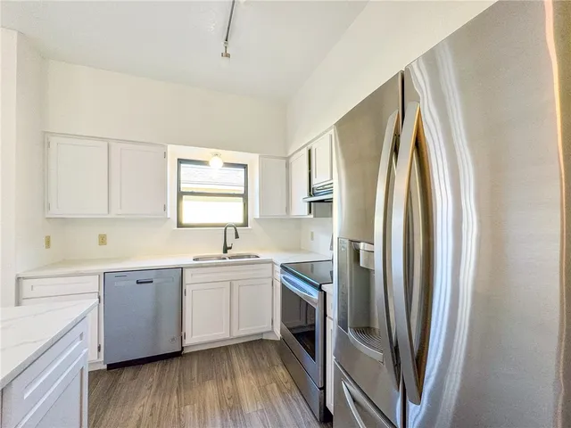 a kitchen with stainless steel appliances a refrigerator a sink a stove and cabinets