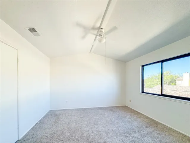 an empty room with a window and a chandelier fan
