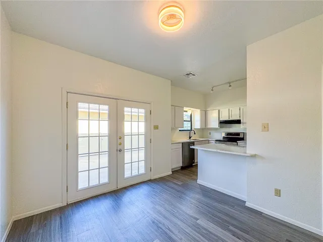 a kitchen with stainless steel appliances granite countertop a stove a sink and white cabinets with wooden floor