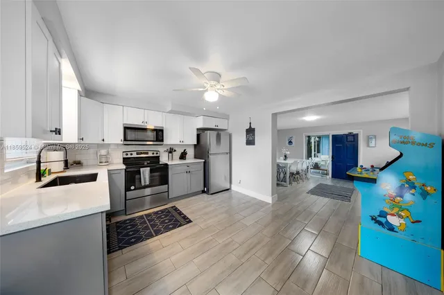 a kitchen with stainless steel appliances kitchen island granite countertop a refrigerator oven a sink dishwasher and white cabinets with wooden floor