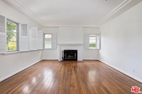 wooden floor fireplace and windows in an empty room