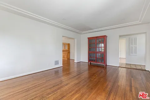 a view of an empty room with wooden floor and closet