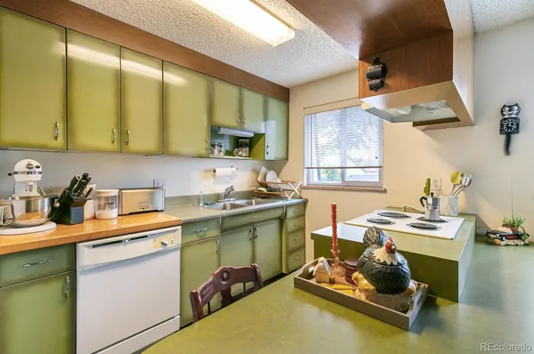 a living room with stainless steel appliances furniture a rug and a kitchen view