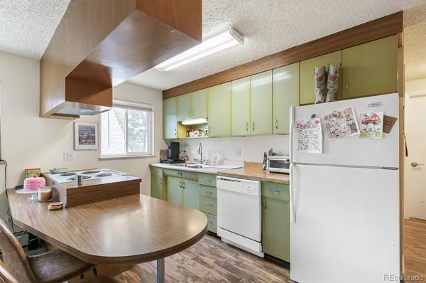 a kitchen with stainless steel appliances granite countertop a sink a stove a refrigerator a dining table and chairs with wooden floor