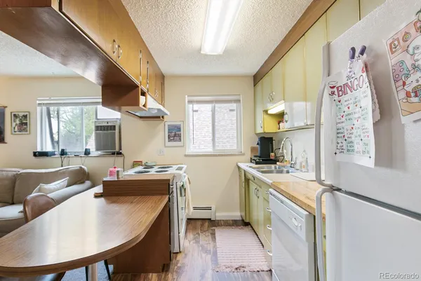 a kitchen with a refrigerator a stove a sink dishwasher with a dining table and chair with wooden floor