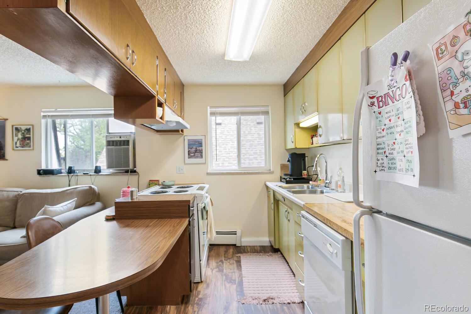 3820 Xavier Street Denver, CO 80212 - Photo 31 of 35 a kitchen with stainless steel appliances granite countertop a sink a stove a refrigerator a dining table and chairs with wooden floor