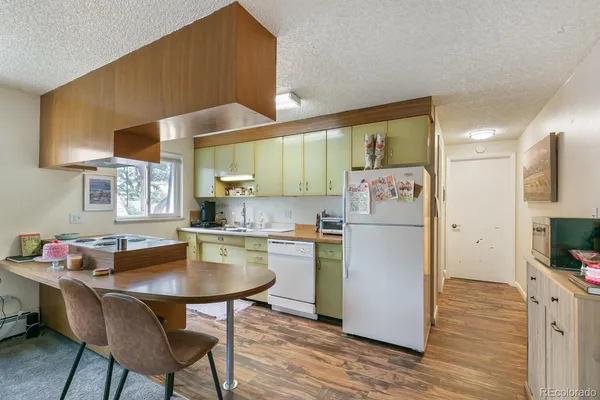 a living room with stainless steel appliances furniture a rug and a kitchen view