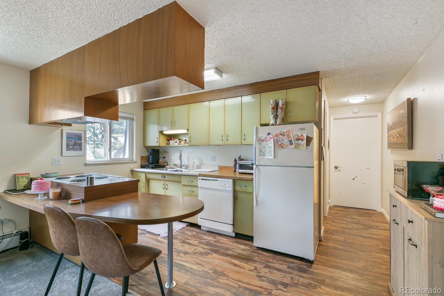 3820 Xavier Street Denver, CO 80212 - Photo 32 of 35 a kitchen with a refrigerator a stove a sink dishwasher with a dining table and chair with wooden floor