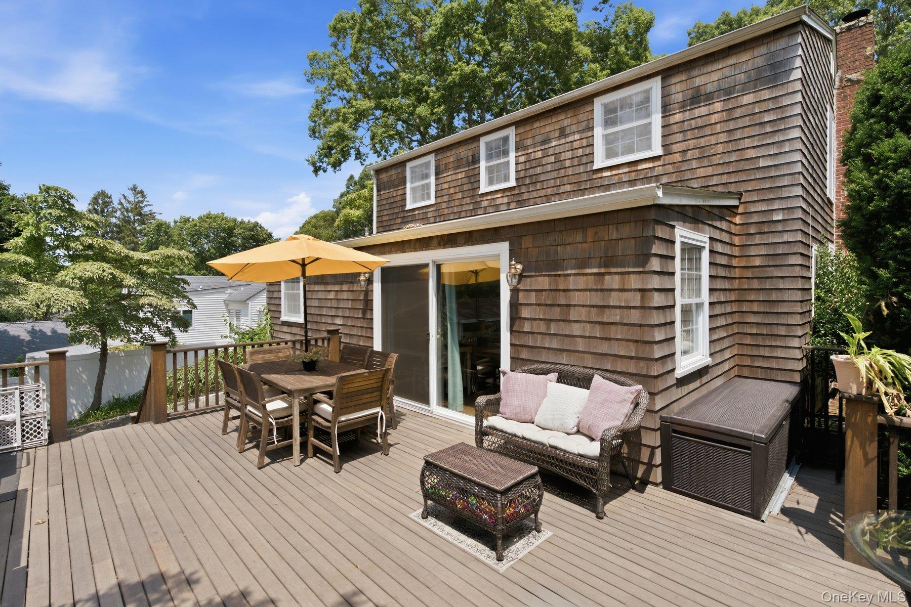 81 Beach Road Wading River, NY 11792 - Photo 17 of 25 a view of a patio with couches and table and chairs with wooden floor and fence