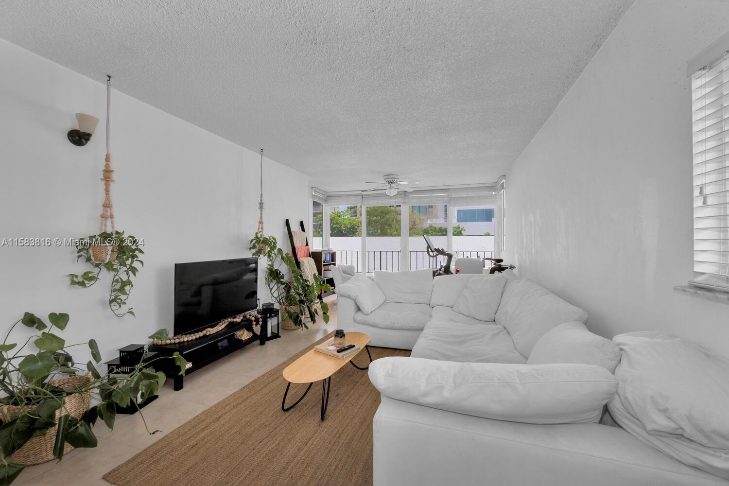 a living room with furniture a flat screen tv and a potted plant