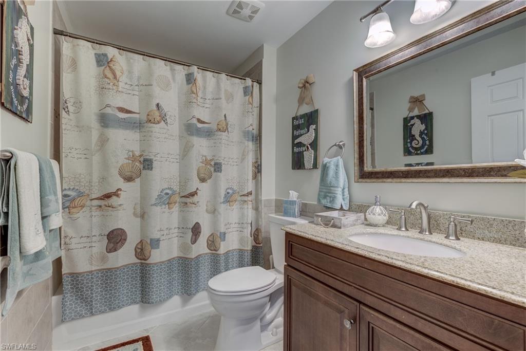 760 Augusta Boulevard, Unit D204 Naples, FL 34113 - Photo 11 of 32 a bathroom with a sink a toilet and shower curtain