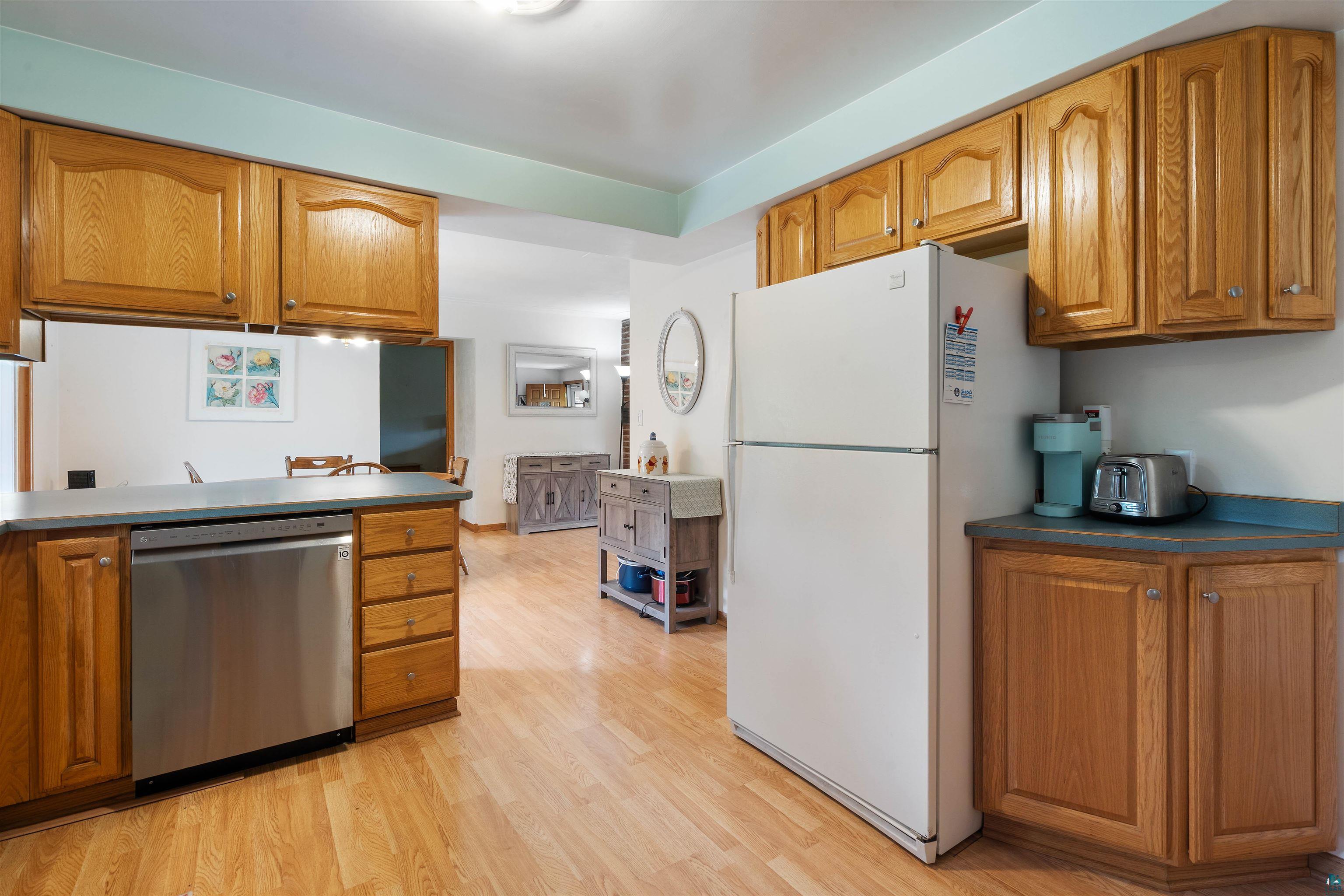 3711 Getchell Road Hermantown, MN 55811 - Photo 8 of 31 Kitchen featuring wood-finish flooring, oak cabinetry, a stainless steel dishwasher, and a light blue countertop