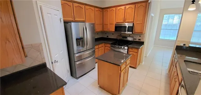 a kitchen with stainless steel appliances granite countertop a refrigerator stove and microwave
