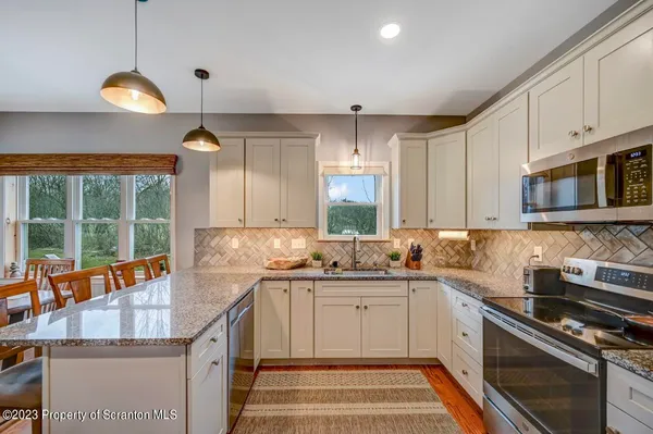 a kitchen with stainless steel appliances granite countertop a sink a stove and a wooden floors