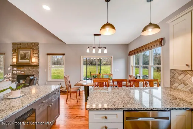 a kitchen with stainless steel appliances kitchen island granite countertop a table chairs in it and a wooden floor
