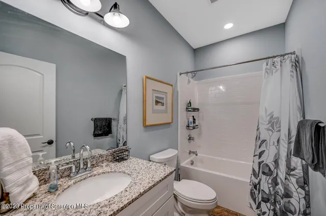 a bathroom with a granite countertop sink a mirror and a toilet