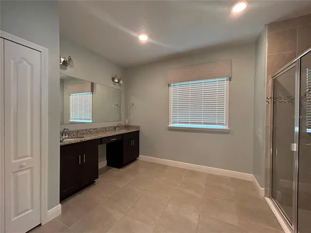 a large bathroom with a granite countertop tub a sink and a large mirror
