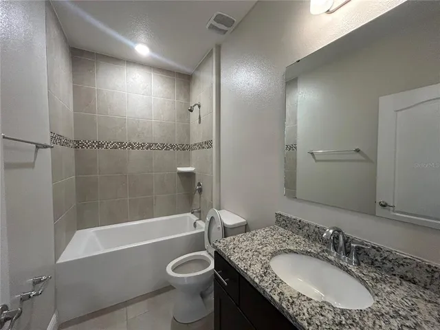 a bathroom with a granite countertop sink toilet mirror and bathtub