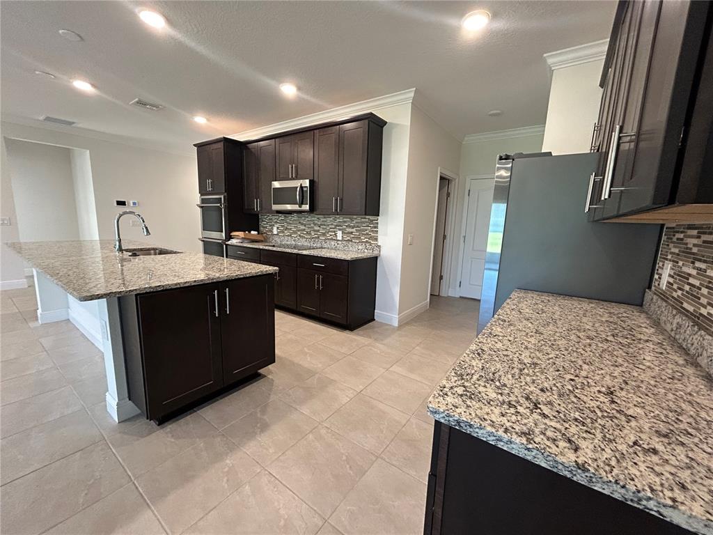24470 Northwest 6th Road Newberry, FL 32669 - Photo 6 of 22 a large kitchen with kitchen island a sink stove and refrigerator