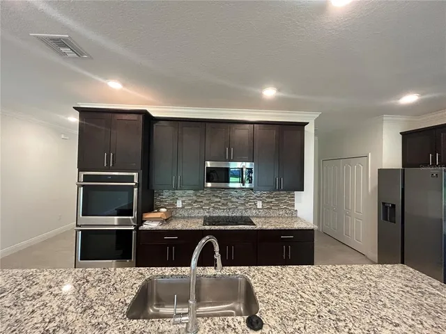 a kitchen with kitchen island granite countertop a refrigerator and a sink