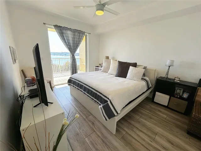 a large bed sitting in a bedroom next to a lamp with wooden floor
