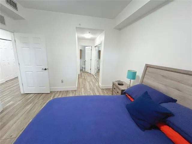 a view of a hallway with wooden floor and a bathroom