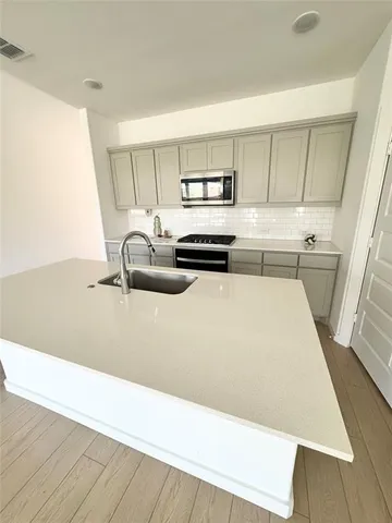 a kitchen with a sink a stove and white cabinets