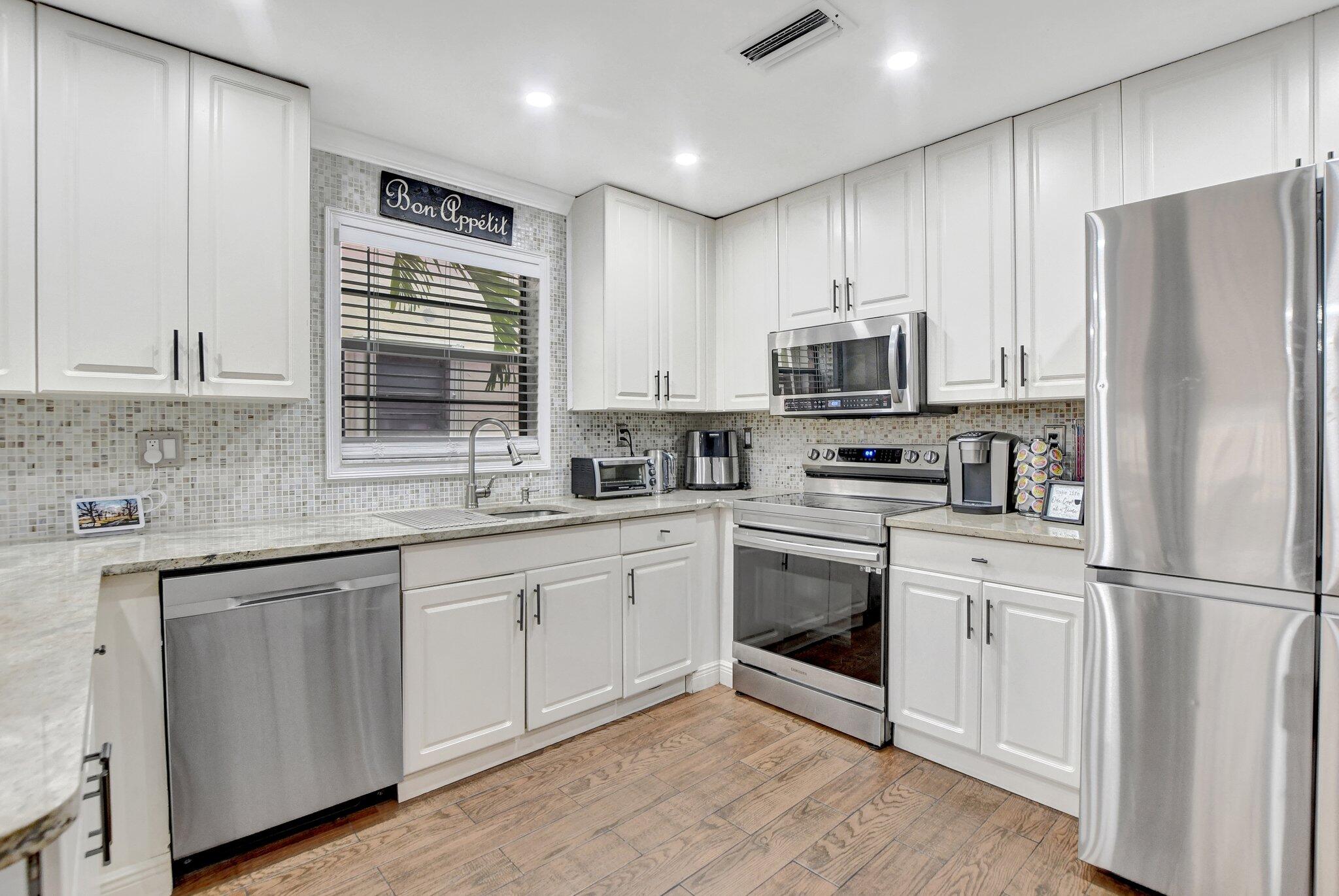23398 Southwest 54th Way, Unit A Boca Raton, FL 33433 - Photo 3 of 29 a kitchen with granite countertop white cabinets and stainless steel appliances